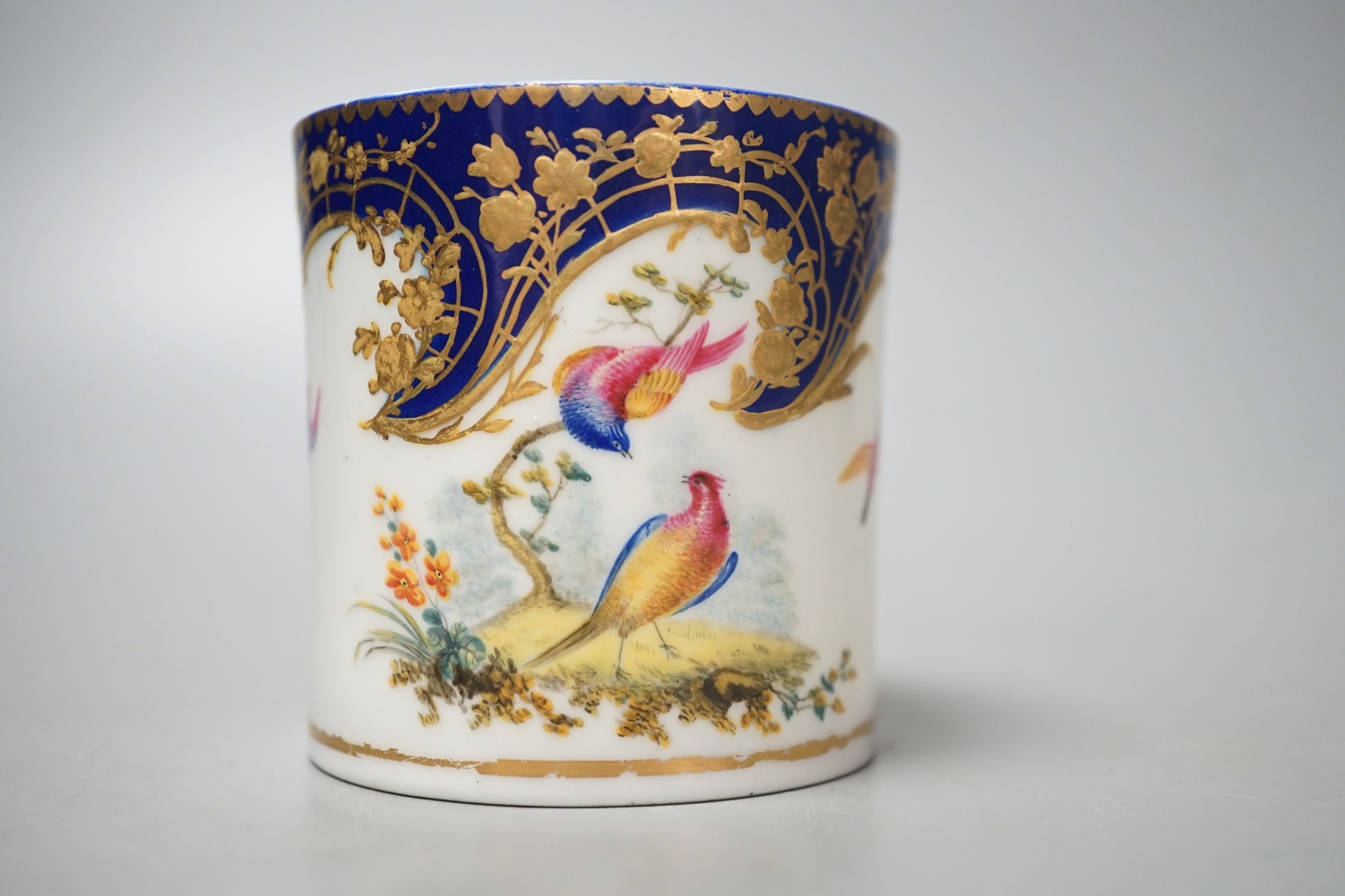 A Sevres coffee can painted with two birds in a tree, and other birds in flight under a richly gilded blue ground date code for 1766